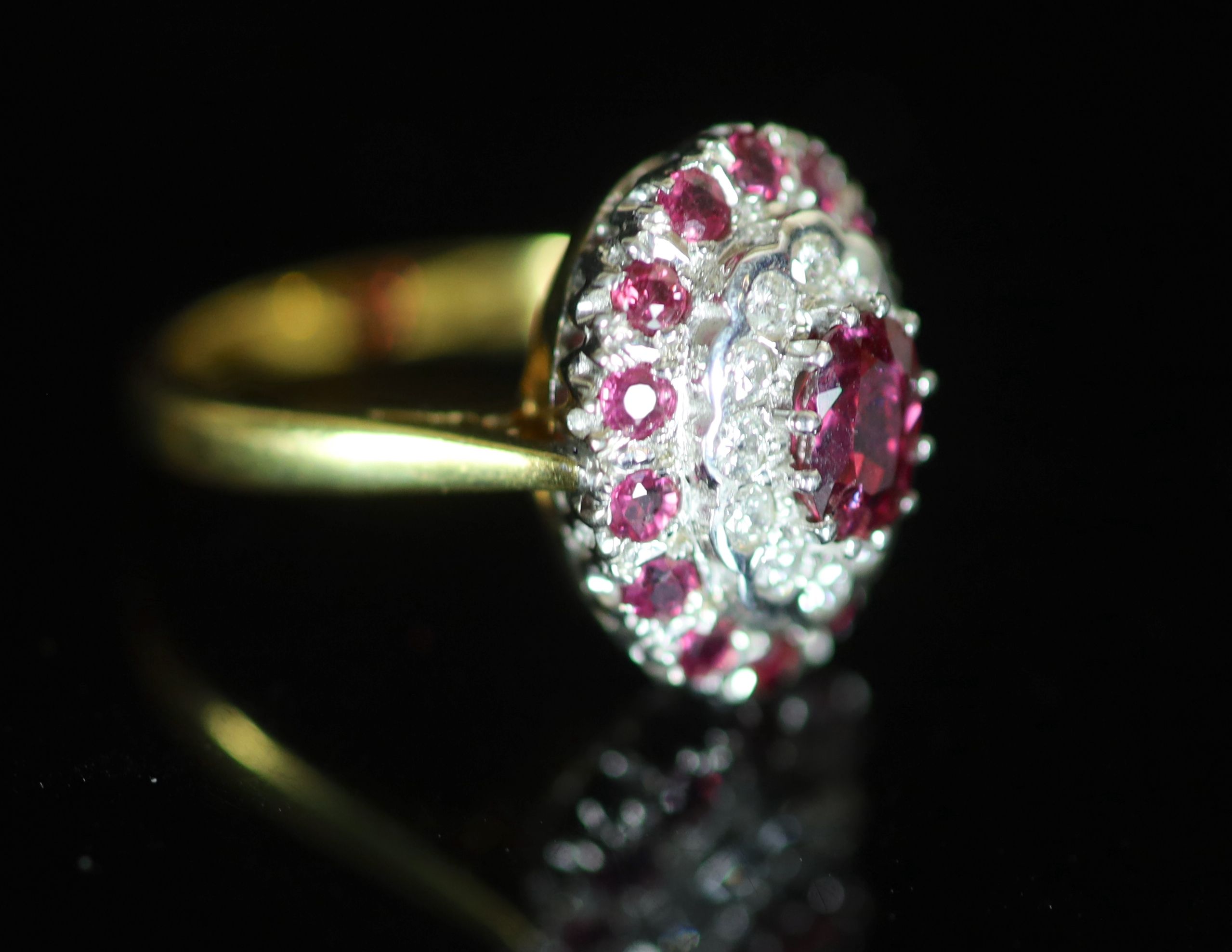 A modern 18ct gold, ruby and diamond set oval cluster ring